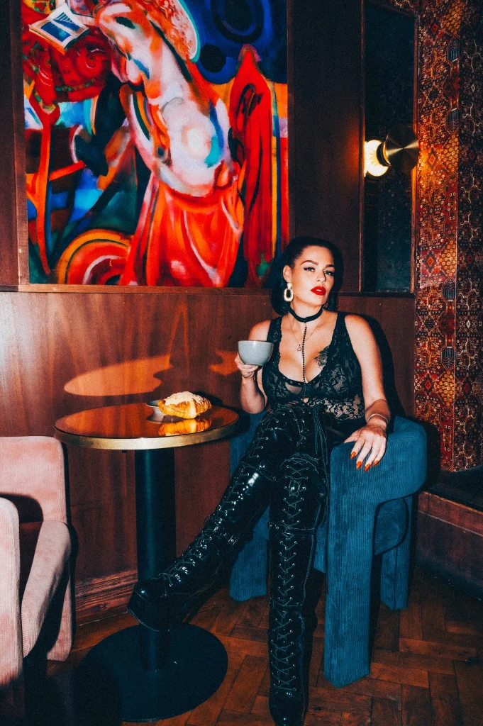 Mistress Charlotte O’Winter taking tea in a velvet armchair