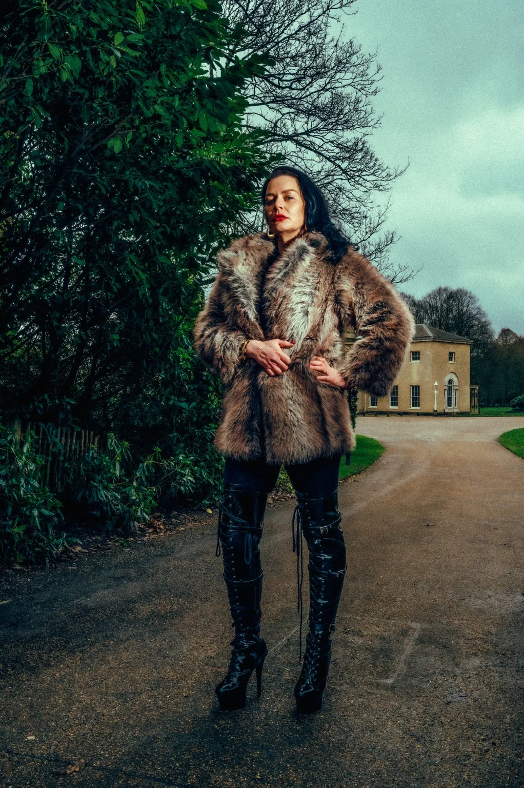 Mistress Charlotte O’Winter in a fur coat and thigh-high boots on a country house drive