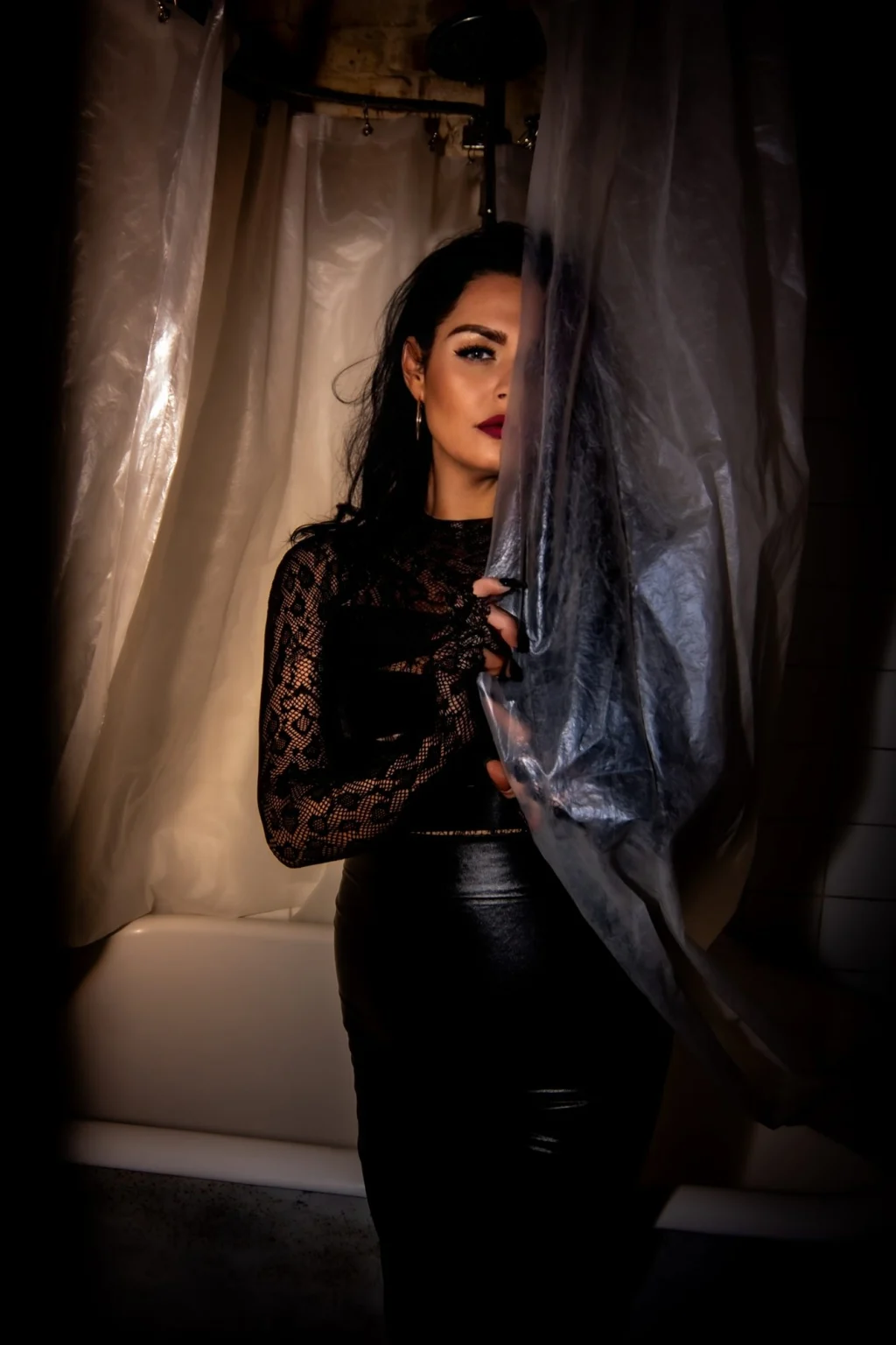 Mistress Charlotte O’Winter half in shadow behind a curtain, black lace