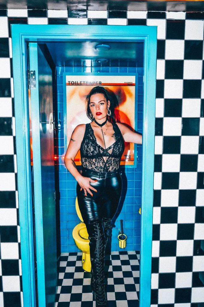 Mistress Charlotte O’Winter in latex and lace in a black-and-white tiled washroom