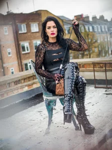 Mistress Charlotte O’Winter seated with a riding crop on a London rooftop, caning mistress
